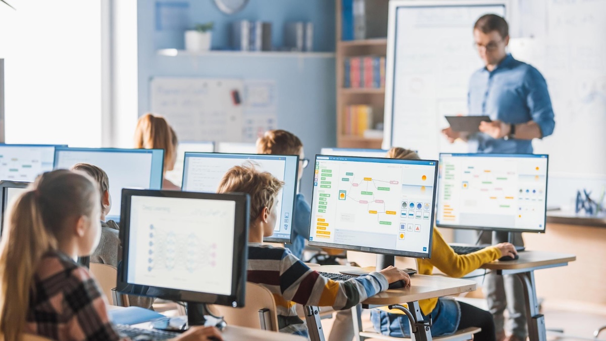 Interactive Infographics in Modern Learning image A teacher stands in front of a computer screen with a teacher in front of him